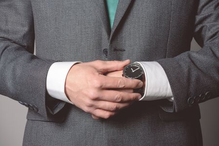 Businessman is checking a time on his wrist watch close up.