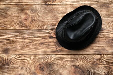 Black leather hat on a brown wooden table flat lay background with copy space.の写真素材