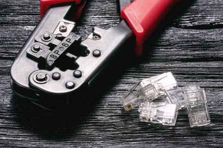 Computer network laying concept. Crimper tool and connectors closeup on black wooden table background.の写真素材
