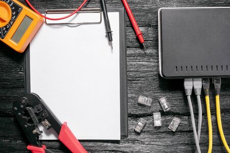 Computer network laying concept. Blank paper page, crimper tool, utp cable, net switch and...
