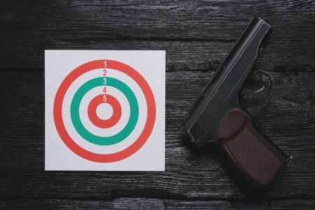 Shooting range concept background. Aim and black pneumatic gun on black wooden background.の写真素材