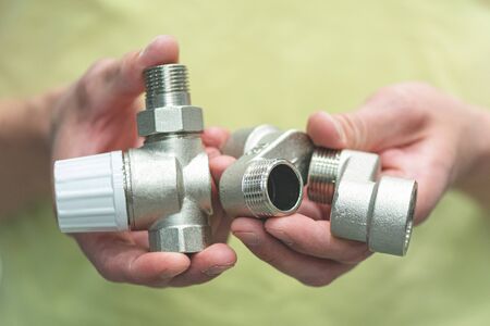 Worker holding in hands a new water valve close up.の写真素材