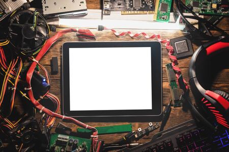 A blank screen digital tablet computer and old computer parts on the wooden flat lay table...