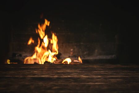 Empty table with a copy space for food for example over a burning fire in a brick fireplace.の写真素材