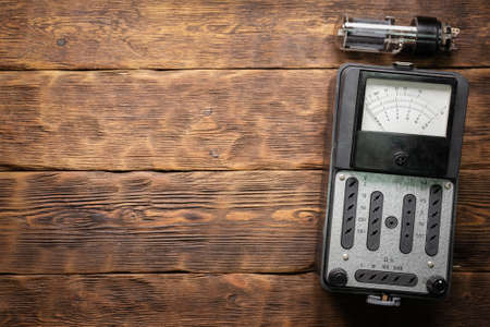 Vacuum tube and retro voltmeter on wooden board flat lay background.の写真素材