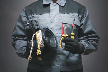 Car audio specialist holding in hands a car audio equipment on dark background.の写真素材
