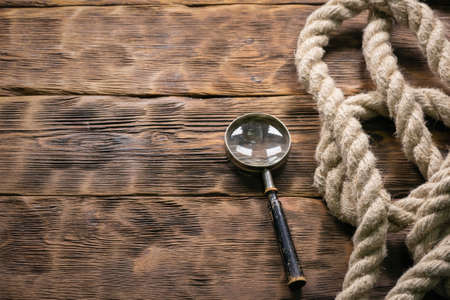 Magnifying glass and rope on the wooden table background with copy space.の写真素材