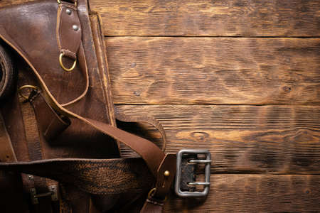 Old leather bag and brown belt on the wooden table background with copy space.の写真素材