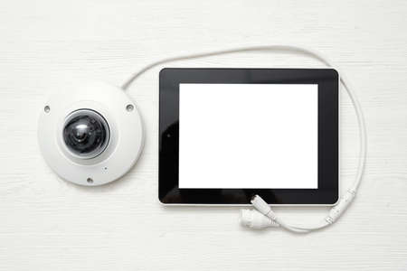 Modern white security camera and blank screen digital tablet on the table background. Video surveillance concept background.の写真素材