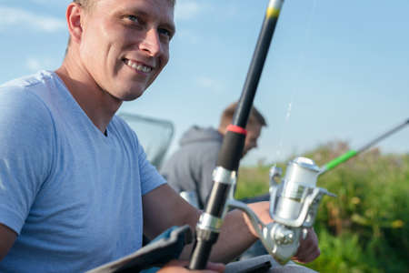 Two friends are fishing on the lake close up.