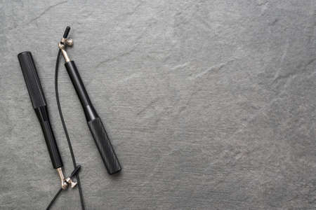 Black jumping rope on the stone floor flat lay background with copy space.