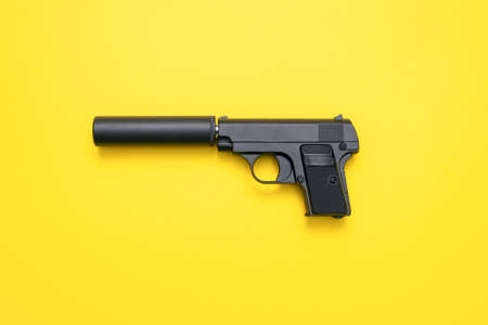 Black airsoft gun on yellow flat lay background.