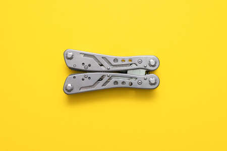 Steel multi tool on the yellow flat lay background.の写真素材