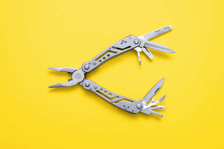 Steel multi tool on the yellow flat lay background.