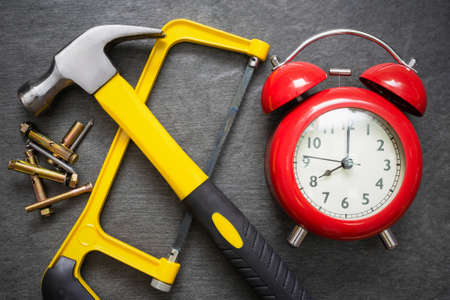 Red alarm clock and work tools on the table. Repair time abstract background.の写真素材