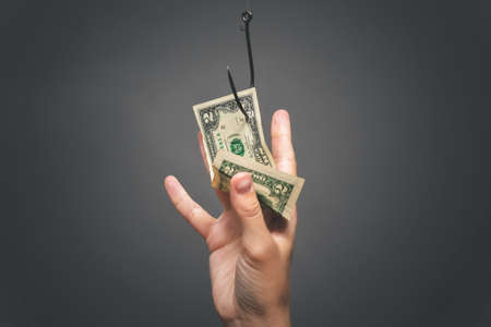 Female hand is trying to catch a dollar currency which hanging on the fish hook. Financial trap.