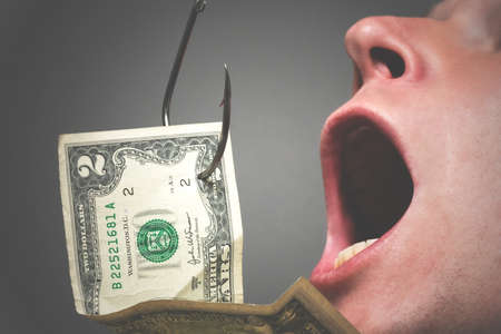 Man with open mouth is trying to catch a dollar on the fish hook close up. Financial trap concept.の写真素材