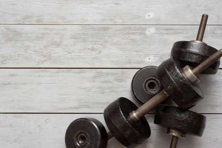Old black dumbbells on a wooden floor background. Simple gym flat lay background with copy space.の写真素材
