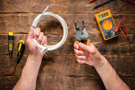 Electrician is holding in hands a cable stripper and wiring.の写真素材