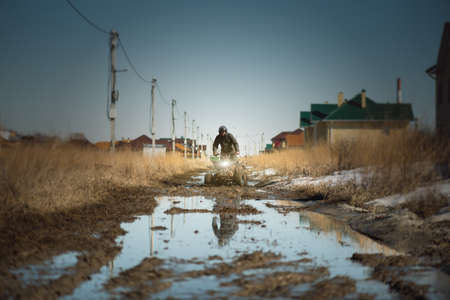 Motor biker is riding a quad bike on the dirty road.の写真素材