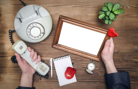 Photo frame with copy space, phone and male hands with wedding ring. Declaration of love. Miss you concept.の写真素材