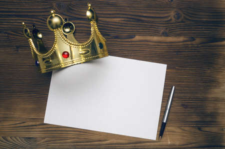 Blank paper sheet with pen and golden crown on wooden table background. VIP agreement. Premium...