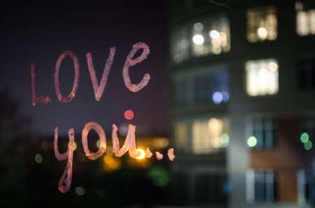 Love you, inscription (text) by lipstick on the window glass in the night. Love concept. Valentine background and love confession.の写真素材