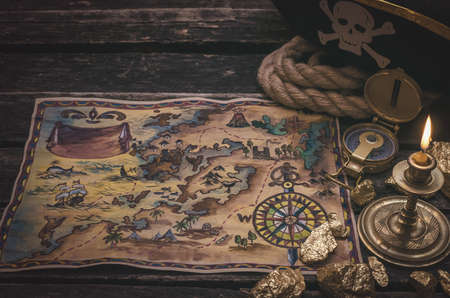 Pirate treasure map, gold nuggets and pirate hat on aged wooden table background. Sea travel.の写真素材