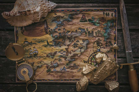 Treasure map, compass and gold nugget on wooden table background.の写真素材
