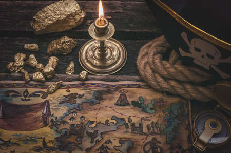 Pirate treasure map, gold nuggets and pirate hat on aged wooden table background. Sea travel.の写真素材