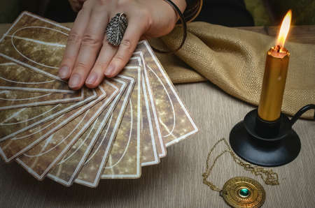Tarot cards on fortune teller desk table. Future reading. Woman fortune teller holding in hands a...