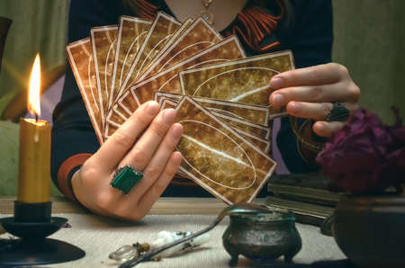 Tarot cards on fortune teller desk table. Future reading. Woman fortune teller holding in hands a deck of tarot cards.の写真素材