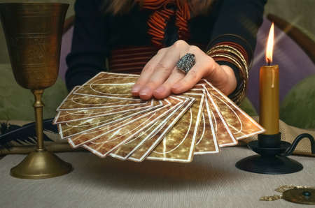 Tarot cards on fortune teller desk table. Future reading. Woman fortune teller holding in hands a deck of tarot cards.の写真素材