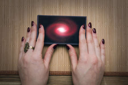 Fortune teller women hands is holding in hands a deck of tarot cards on desk table background....