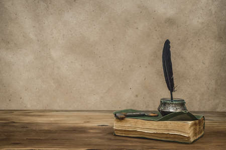 Old book and feather pen with inkpot and rusty key on retro wooden table background with copy space. Writer table concept. Education. Back to school. Memoirs.の写真素材