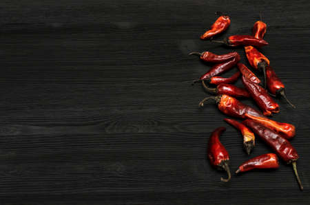 Heap of dry red chili pepper on black kitchen table surface background with copy space. Spicy food.の写真素材