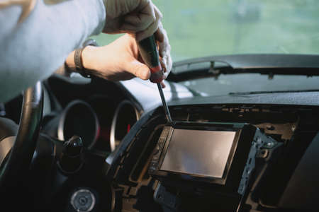 Auto electrician is installing a car radio sound system close up.