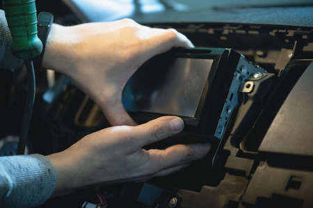 Auto electrician is installing a car radio sound system close up.