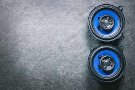 A car audio loudspeaker on dark flat lay background.