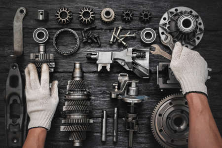 Car gearbox spare parts and car service worker hands with wrenches on the black flat lay background.の写真素材