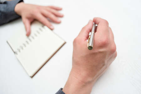 Businessman with pen is sitting by the desk close up.
