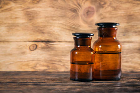Brown glass bottles with liquid on the wooden table background.の写真素材
