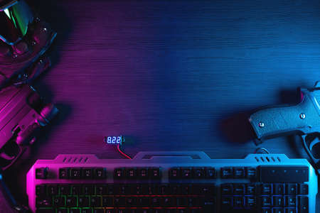 Toy guns, glasses and computer keyboard on the flat lay table background in the neon lights....