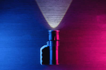 Pocket flashlight on the table in the neon lights top view background.の写真素材