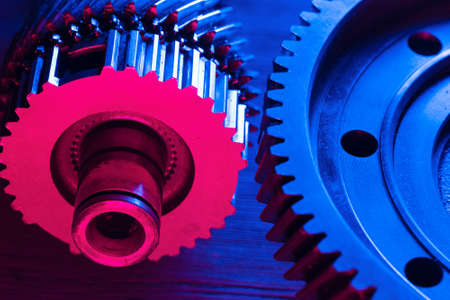Disassembled car gearbox parts close up in the neon lights.