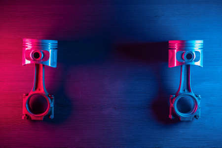 Old car engine pistons with connecting rod on the car service workbench background in the neon lights.の写真素材
