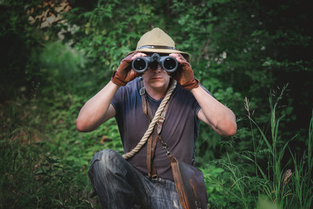 Adventurer man is looking through binoculars close up.の写真素材