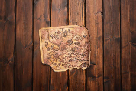 Old treasure map on the brown wooden table background.