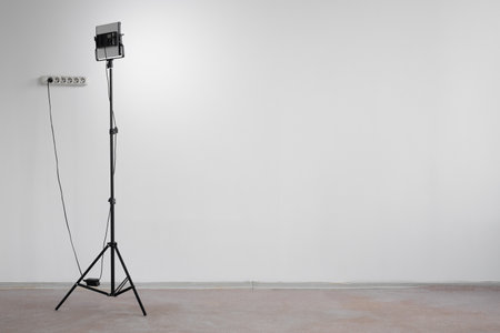 Led light spotlight on a tripod on a gray wall background with copy space.の写真素材