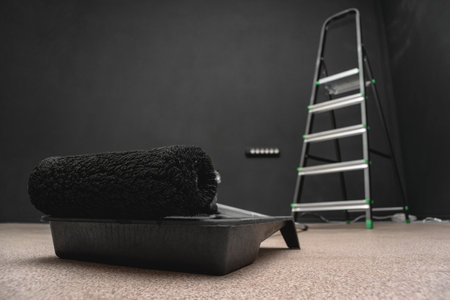 Paint roller, paint and step ladder on the black color wall background.の写真素材
